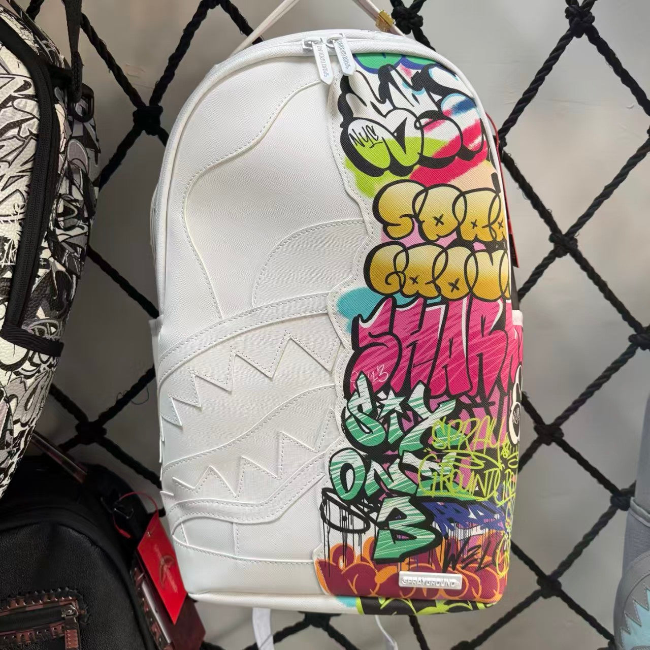 White Backpack with 3D Stitched Shark Mouth and Colorful Graffiti Splice Design