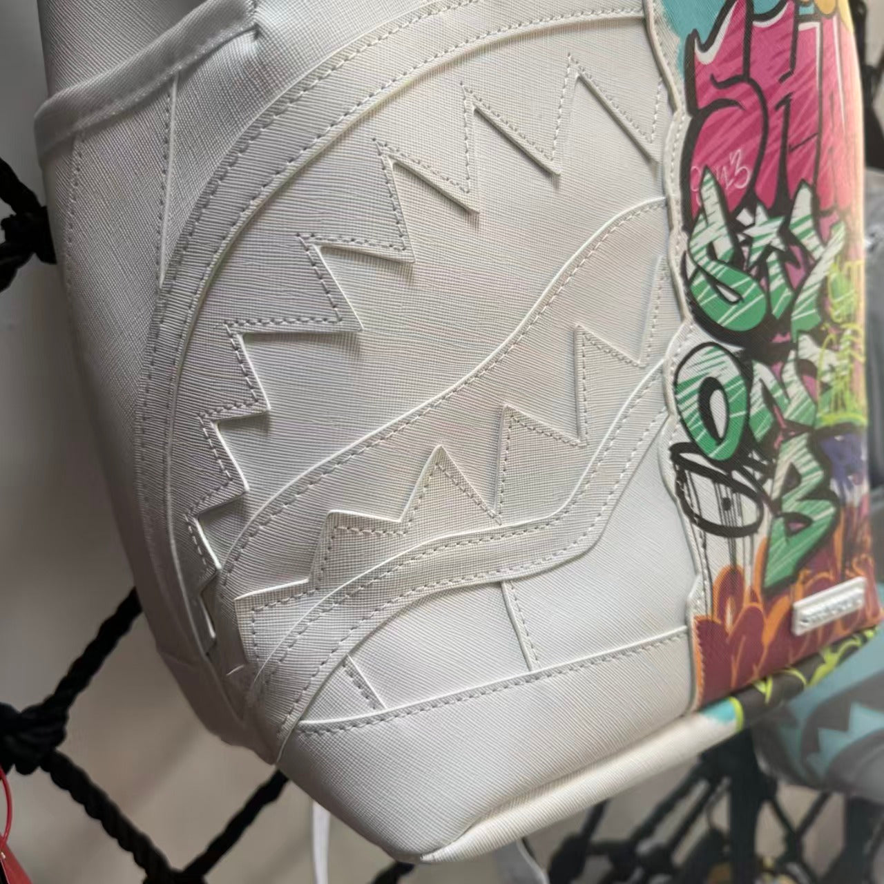 White Backpack with 3D Stitched Shark Mouth and Colorful Graffiti Splice Design